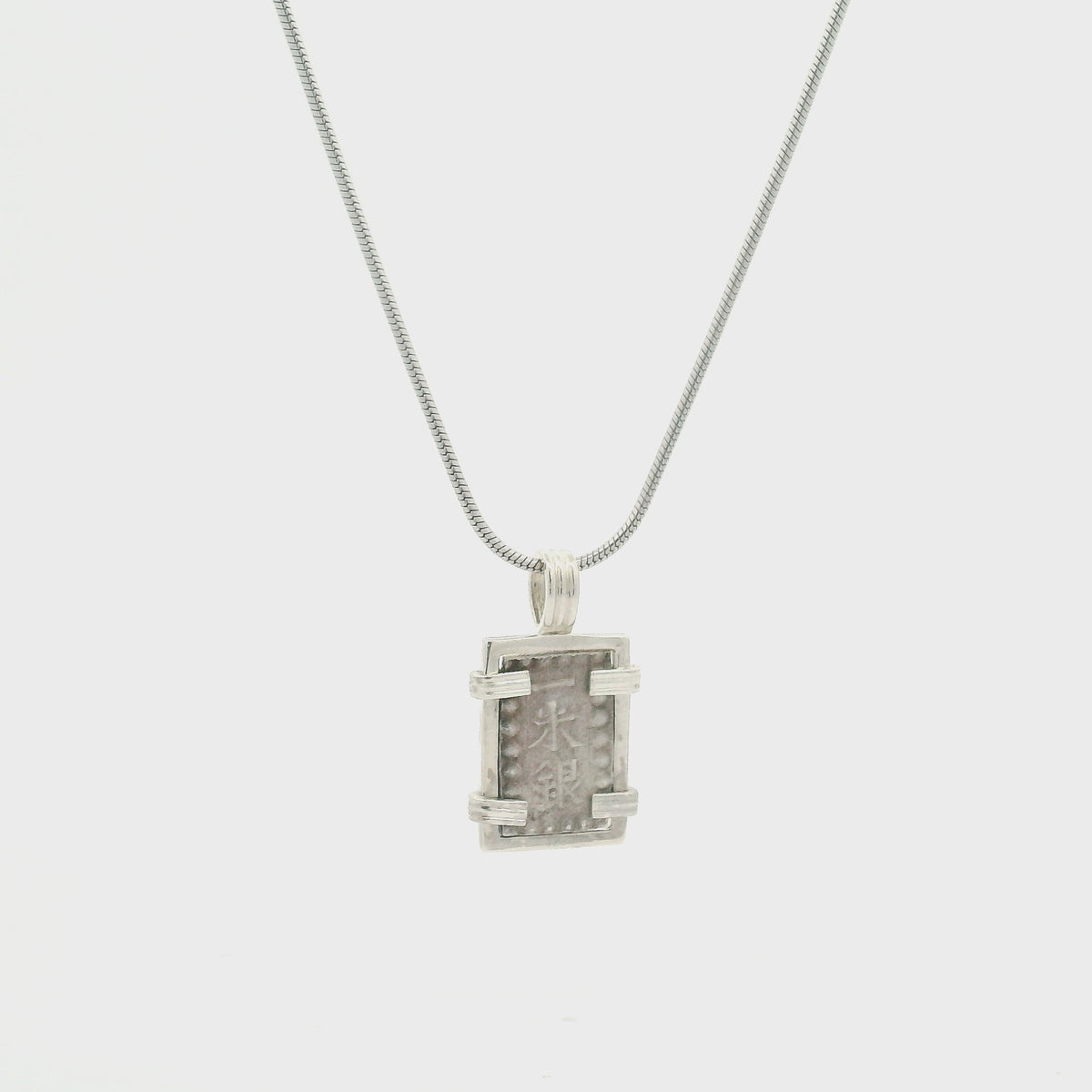 Rotating Silver rectangular Japanese Samurai-era coin pendant set in sterling silver.