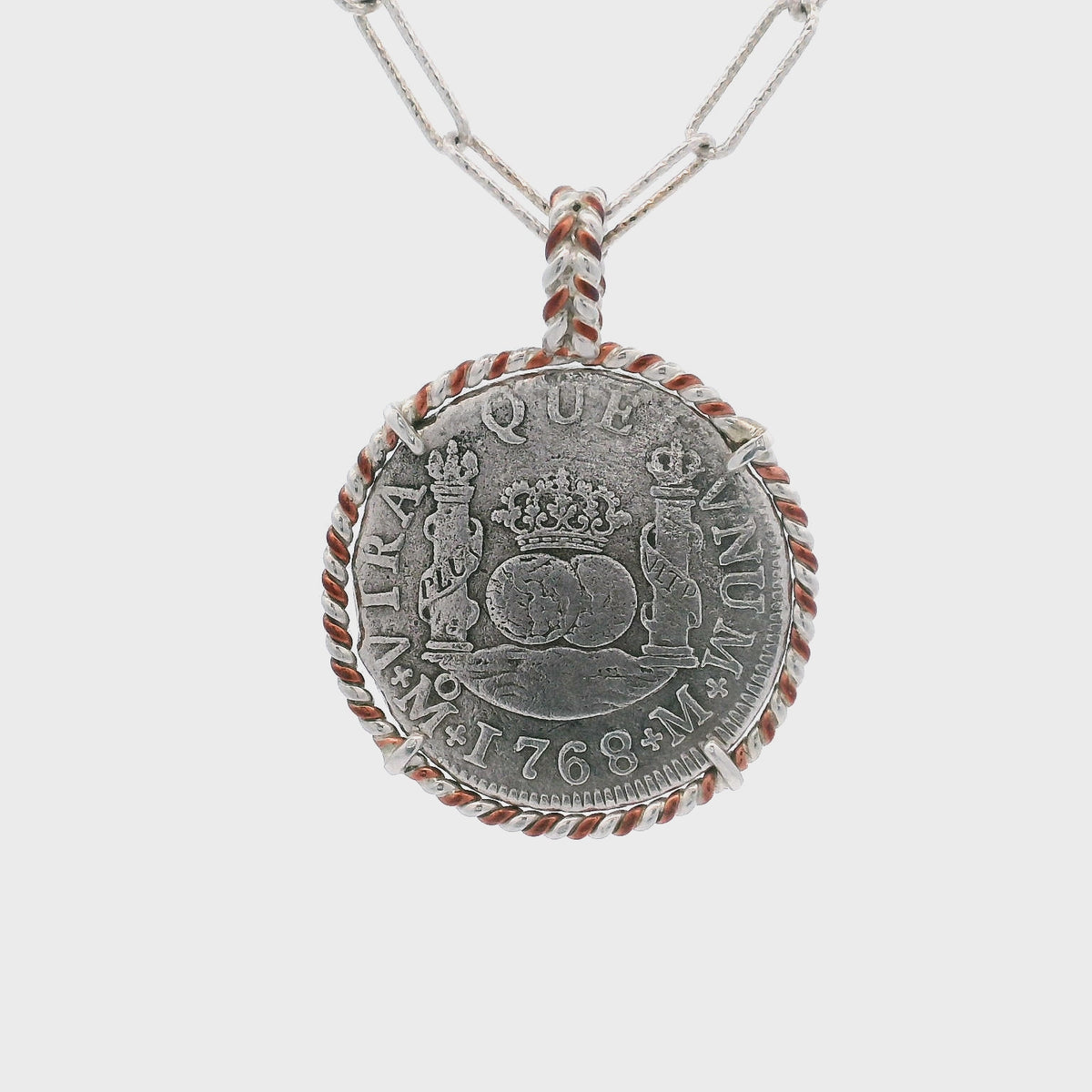 Rotating Silver Spanish coin pendant set in twisted copper and sterling silver wire.